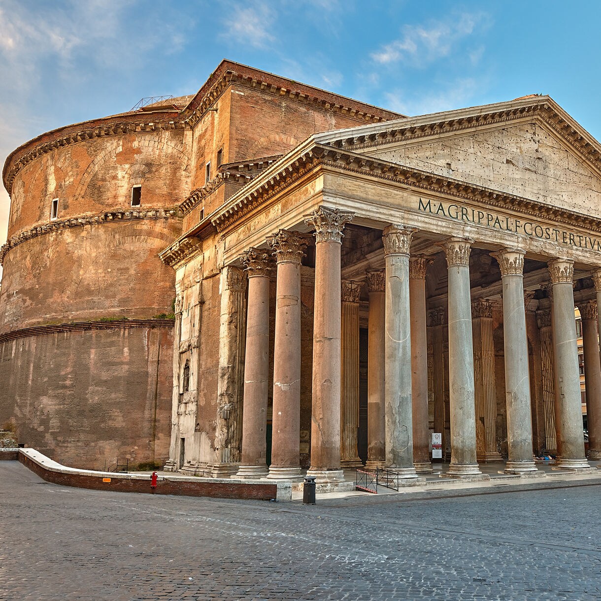 The Pantheon in Rome with its grand portico of Corinthian columns and massive brick rotunda under a clear sky
