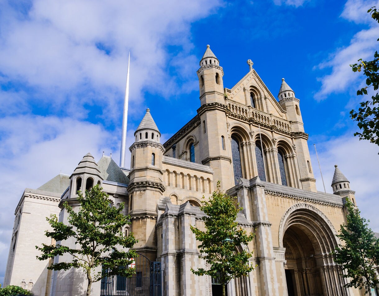 St. Anne’s Cathedral in Belfast with its grand stone façade, arched entrance and tall modern spire rising into the sky.