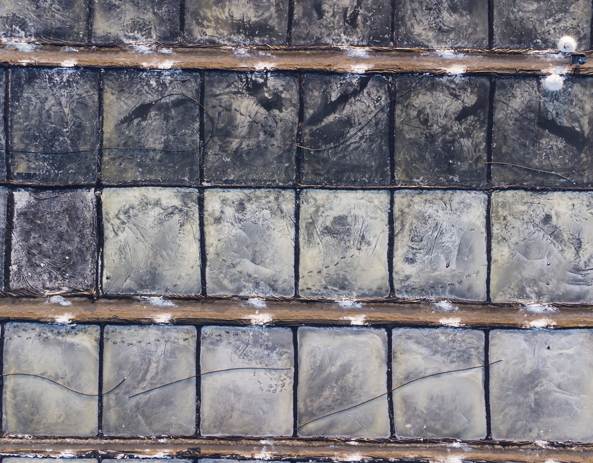 Aerial view of rectangular salt evaporation ponds in neat rows, showcasing earthy tones and crystallized edges.