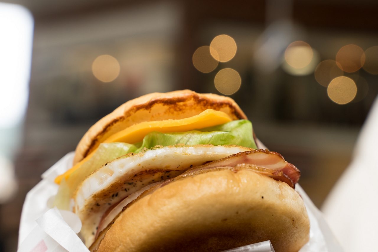 Close-up of a Sasebo burger with bacon, egg, lettuce, cheese and a toasted bun.