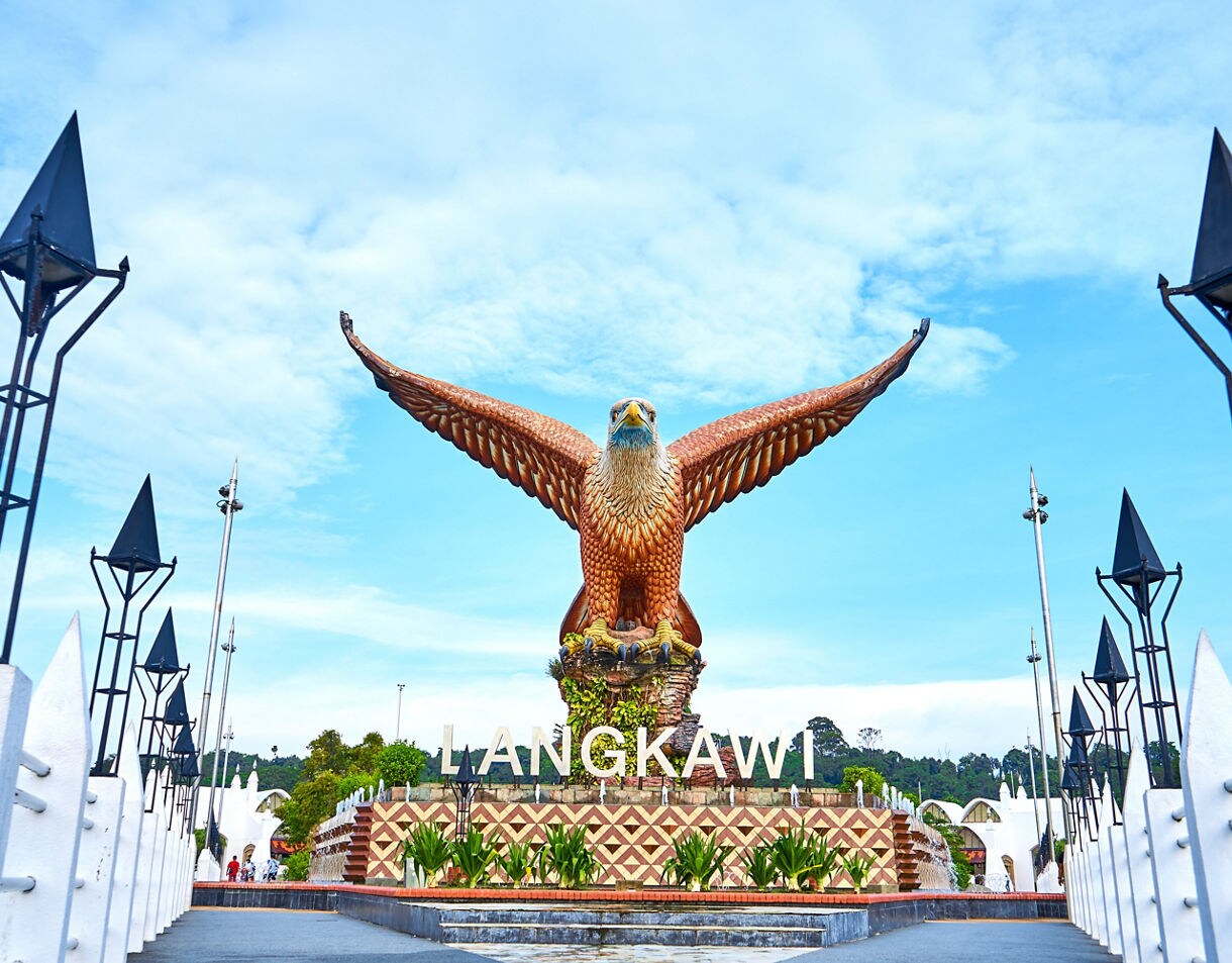 Massive eagle statue with outstretched wings at Eagle Square in Langkawi, Malaysia, set against a bright blue sky.