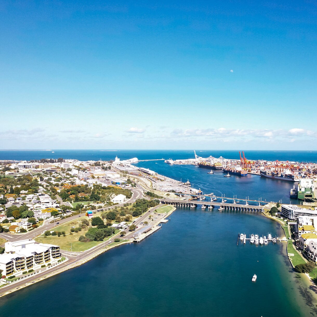 Aerial view of Fremantle Port and Swan River with cargo cranes, ships, marinas and coastal suburbs under a clear blue sky.