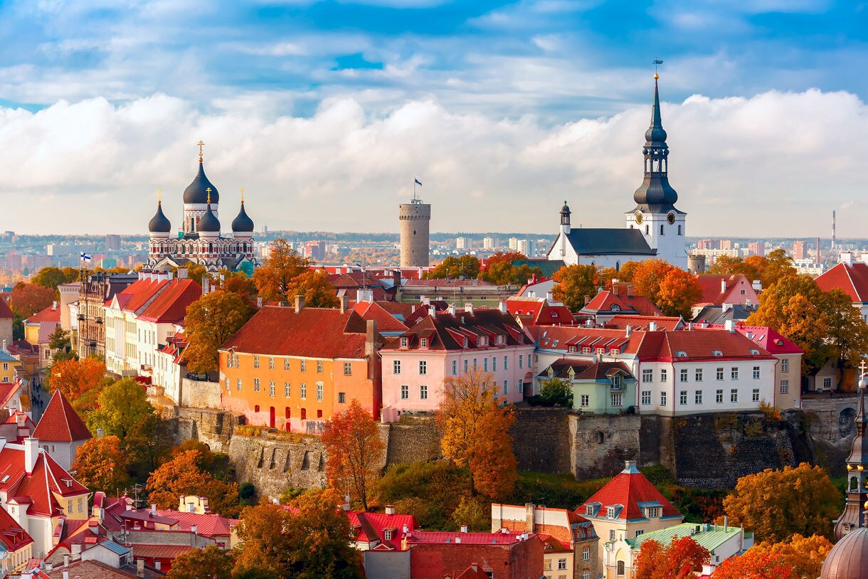 Panoramic view of Toompea Hill in Tallinn, Estonia, showing Alexander Nevsky Cathedral’s onion domes, a medieval stone tower and church spires surrounded by historic pastel buildings and autumn trees.