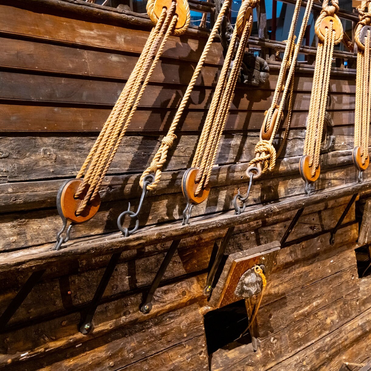 Close-up view of the Vasa warship’s wooden hull with detailed rigging, ropes and pulley blocks preserved inside Stockholm’s Vasa Museum.