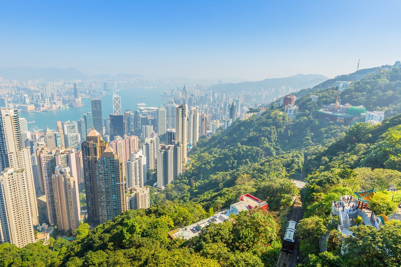 Aerial view from Victoria Peak showing Hong Kong’s skyline, harbor and skyscrapers rising from the forested mountainside.
