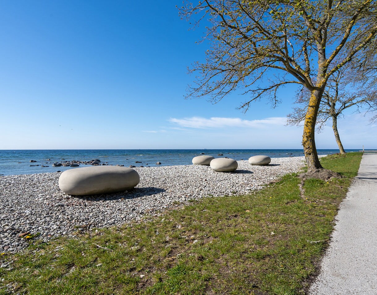 Sculpted stone boulders on a pebble beach in Visby with the Baltic Sea and a clear blue sky.