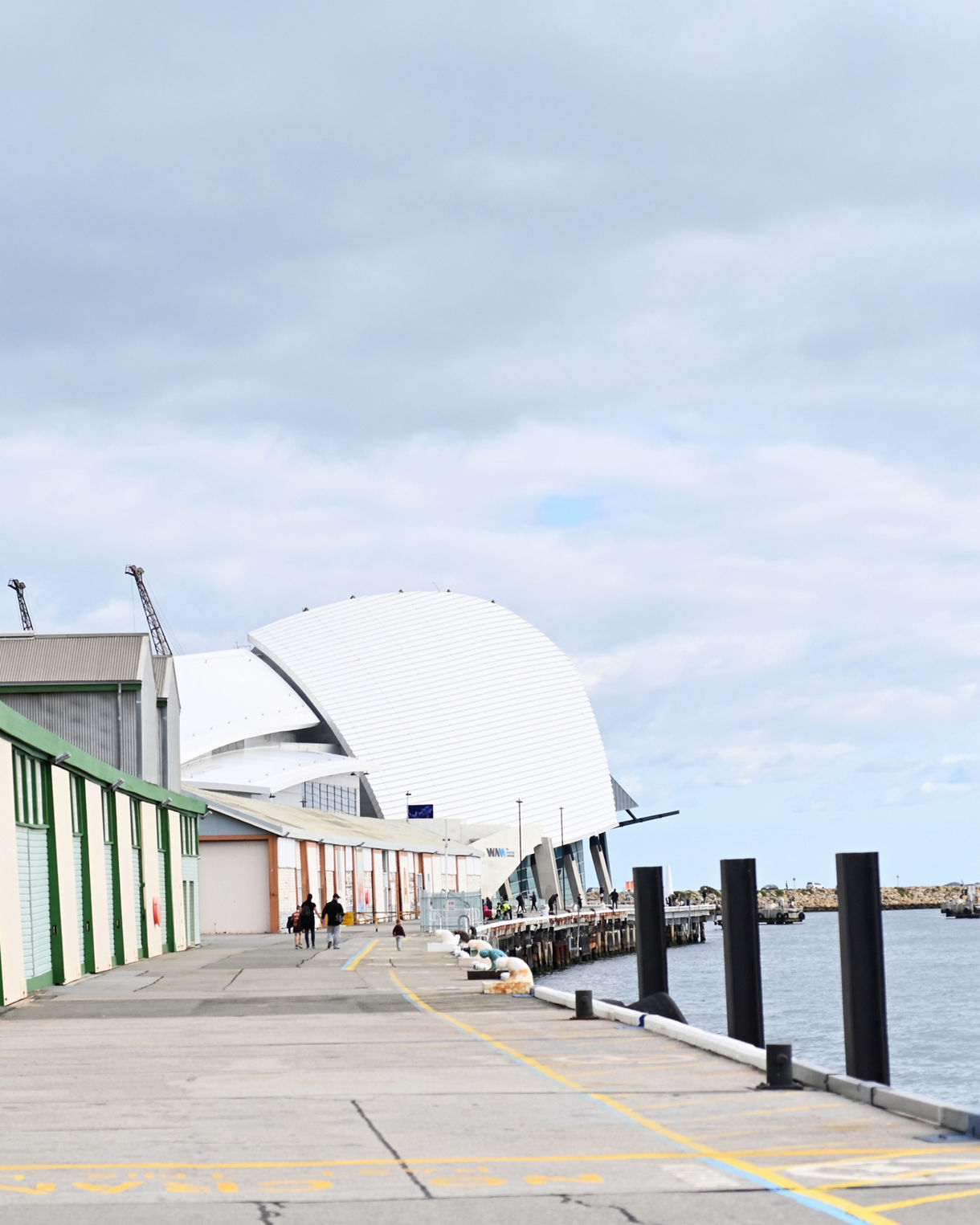 Fremantle’s waterfront promenade leading to the modern white-domed Western Australian Maritime Museum under a cloudy sky.