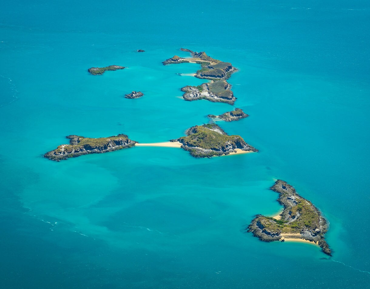 Aerial view of the Buccaneer Archipelago showing clusters of rocky, green-topped islands surrounded by bright turquoise ocean and small sandy coves.