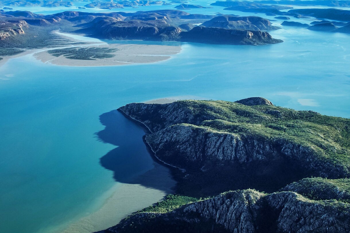 Aerial view of Yampi Sound featuring rugged green headlands, winding tidal channels and wide stretches of bright blue water.