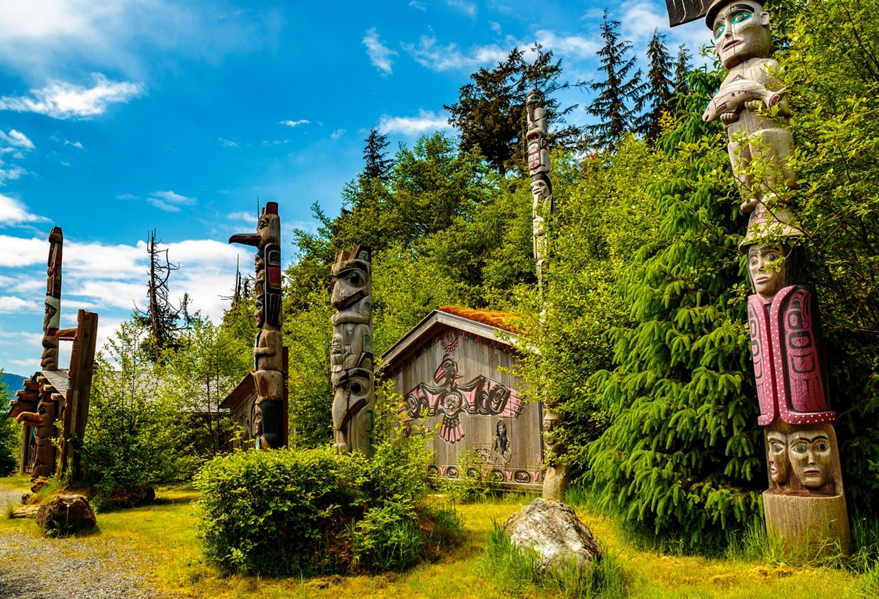 Close-up of a vibrant totem pole at Saxman Native Village, featuring intricate carvings and bright colors.