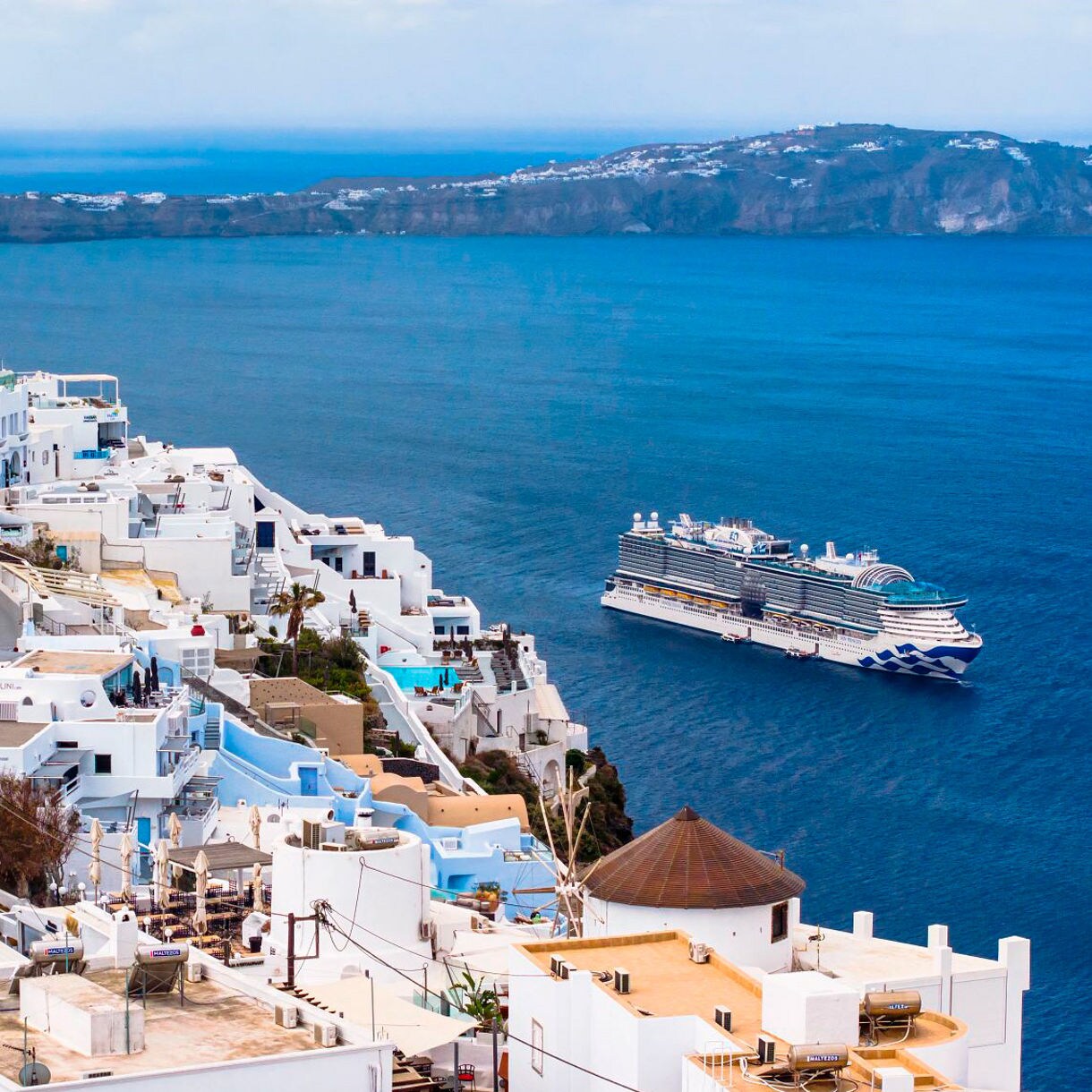 Santorini's blue-domed churches with vibrant pink bougainvillea and stunning sea views.
