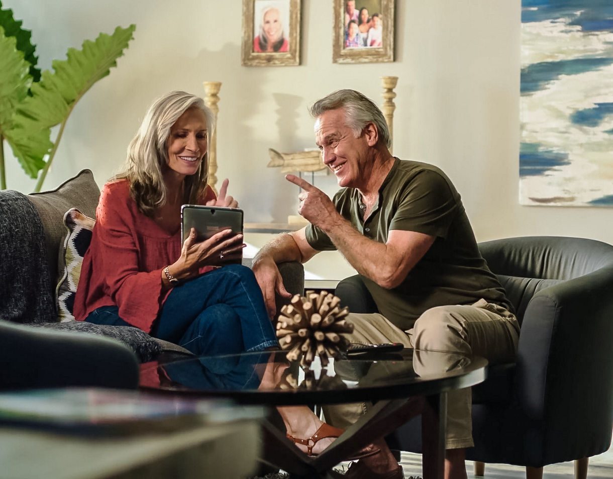 A crew member in uniform serving food to two seated guests at an informal dining area aboard a Princess cruise ship.