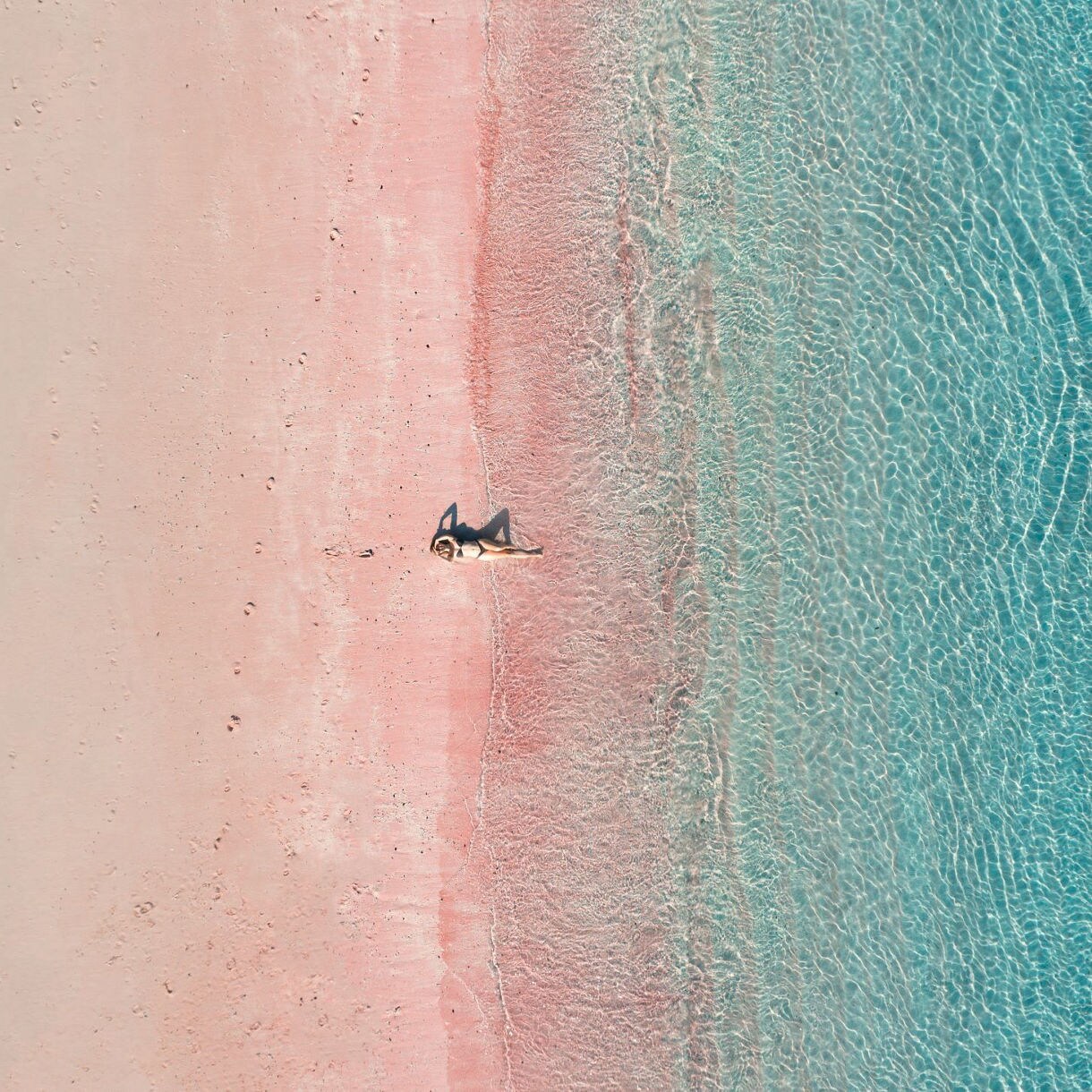 Aerial view of a Caribbean pink beach featuring a solitary person enjoying the serene landscape.