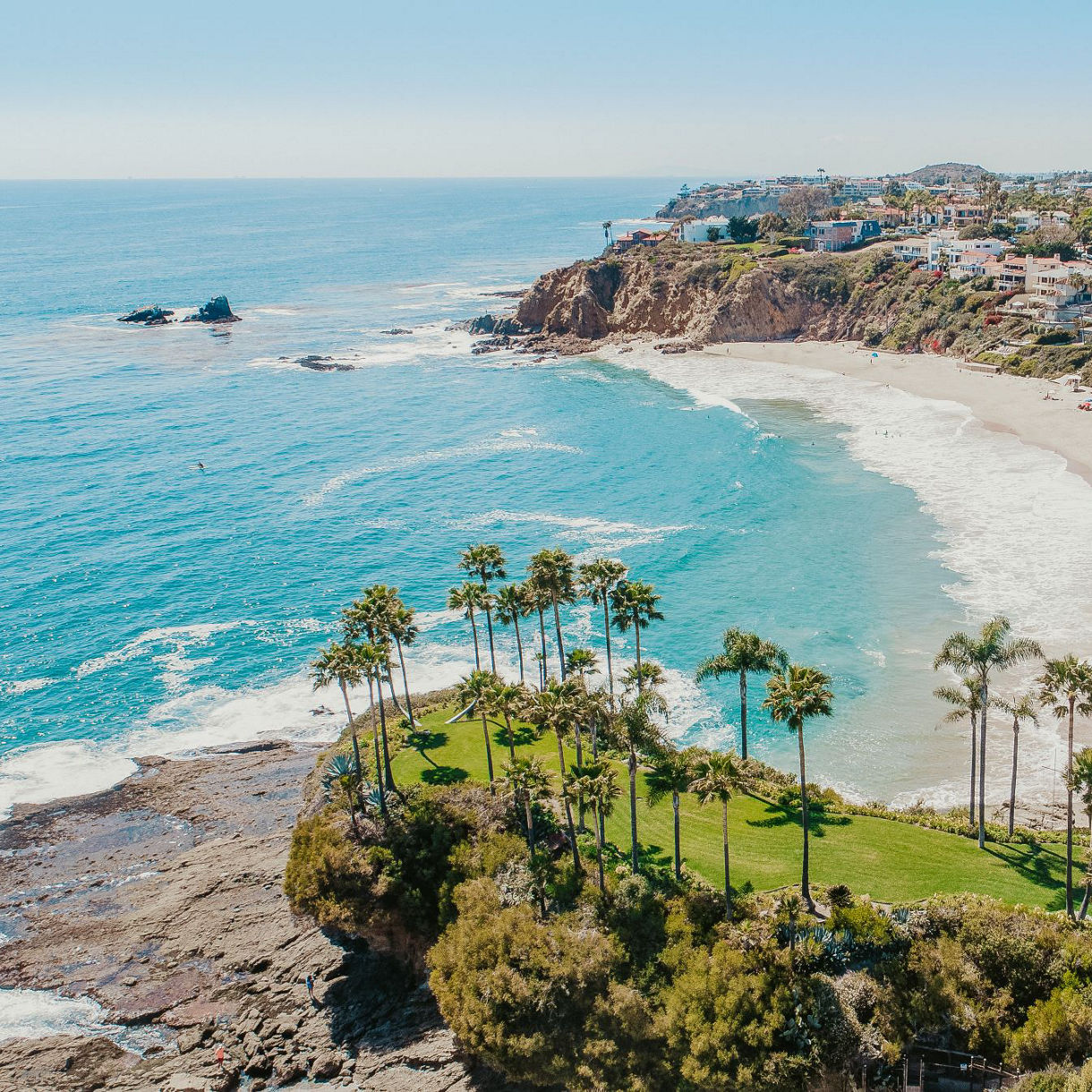 This view of Laguna Beach, California, captures the turquoise waters, palm trees, rocky shores and a charming seaside neighborhood.