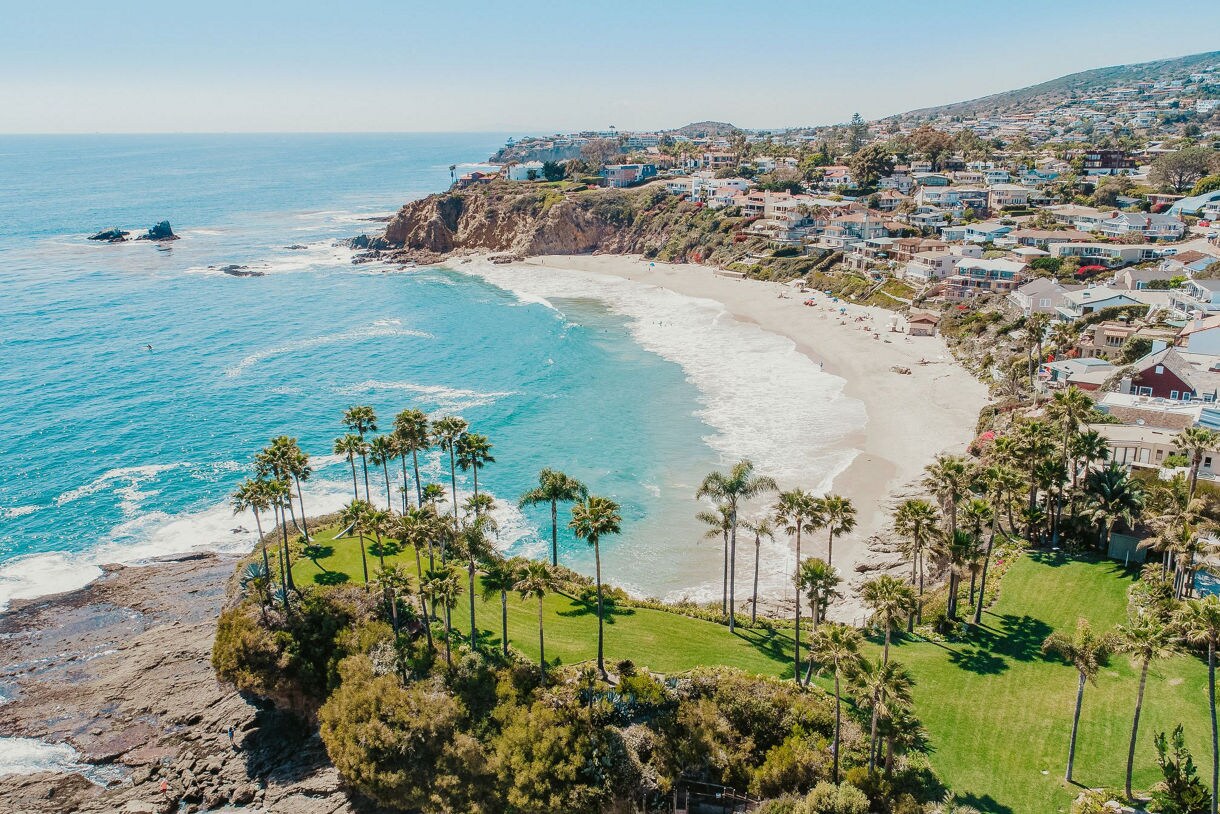 This view of Laguna Beach, California, captures the turquoise waters, palm trees, rocky shores and a charming seaside neighborhood.