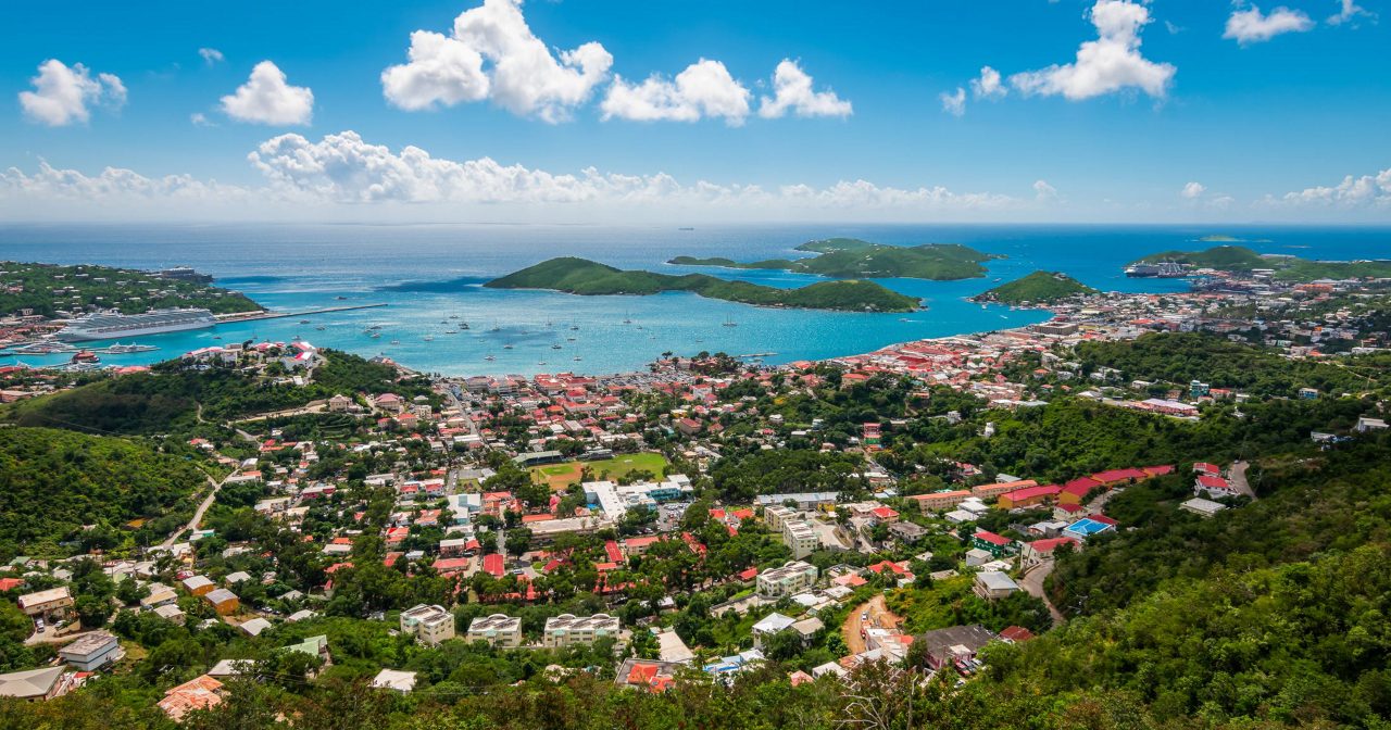 Aerial view of Charlotte Amalie town with red-tiled roofs spread across green hills overlooking turquoise harbor with small islands
