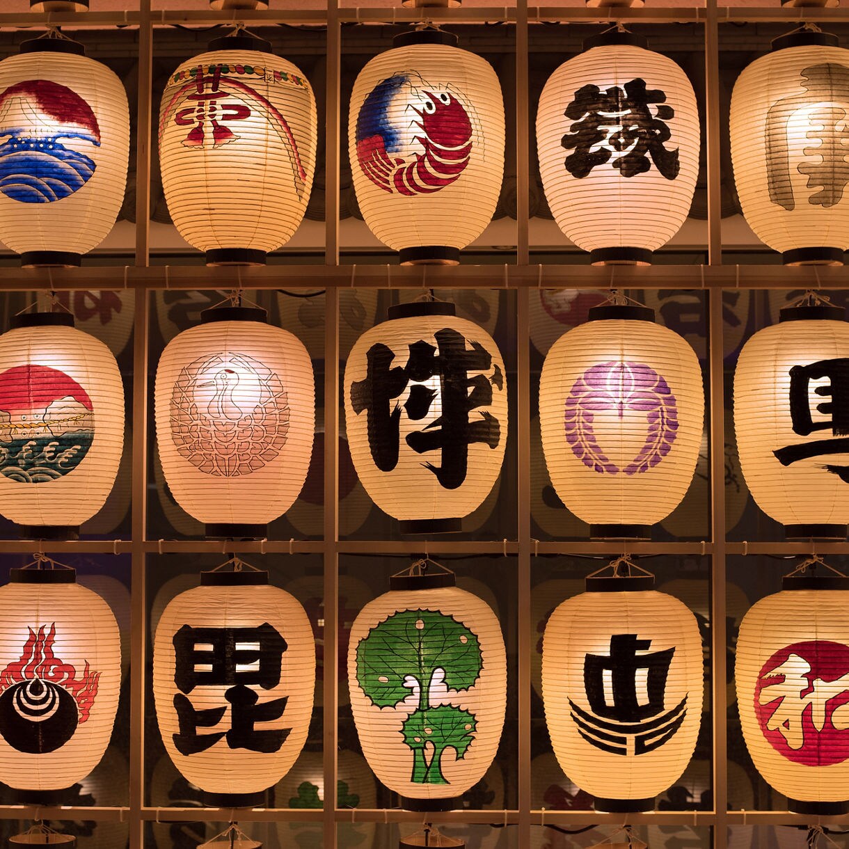 Rows of illuminated Japanese paper lanterns featuring calligraphy and traditional artwork.