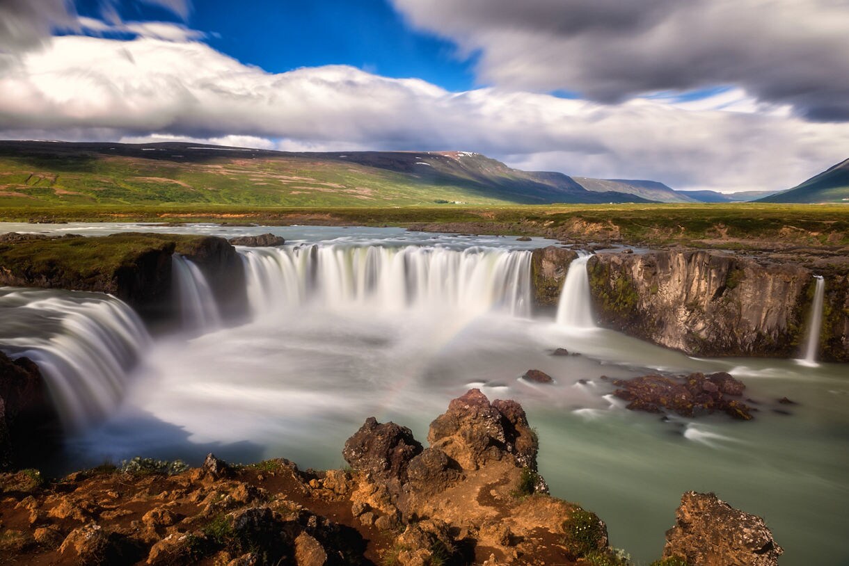 Waterfall with mountains behind on a cloudy day