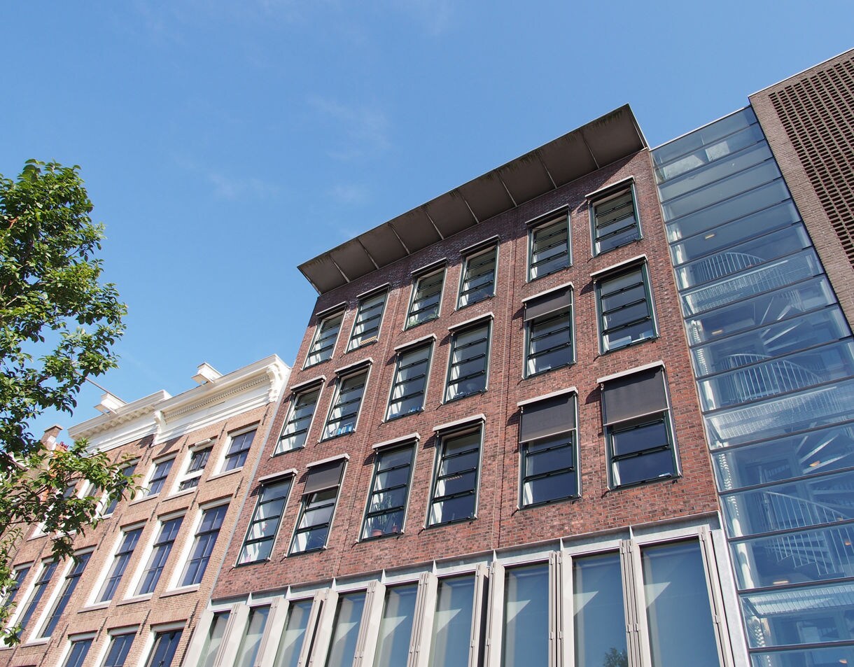 Exterior of the Anne Frank House in Amsterdam showing brick facade and modern glass extension.