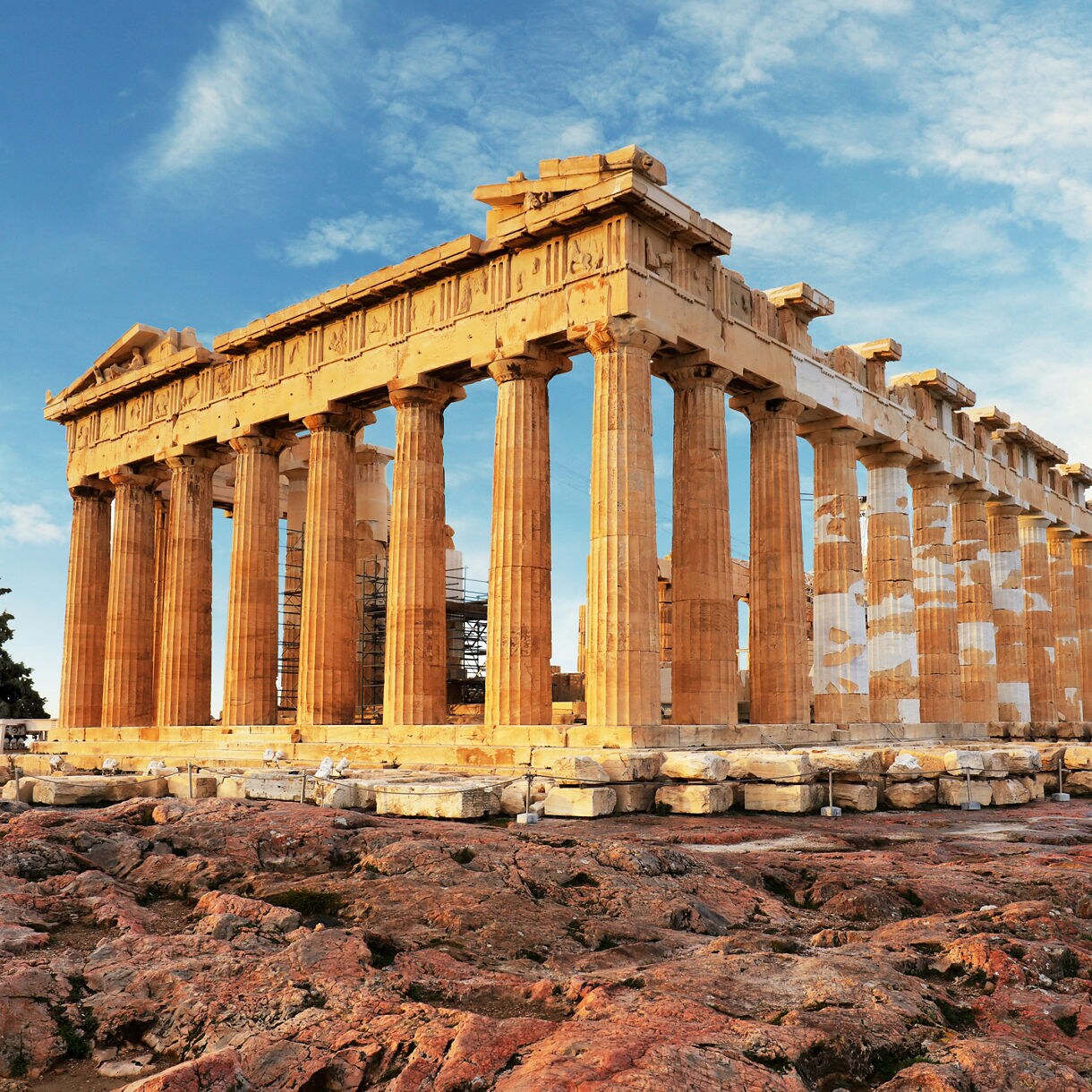 The Parthenon temple on the Acropolis, its tall marble columns glowing under a bright blue sky.