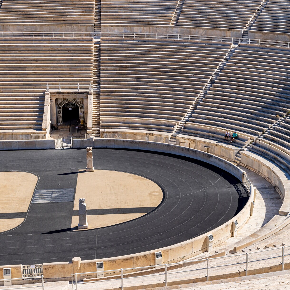 Curving road running alongside a still lake with rolling barren hills and soft evening light in the Arctic landscape.