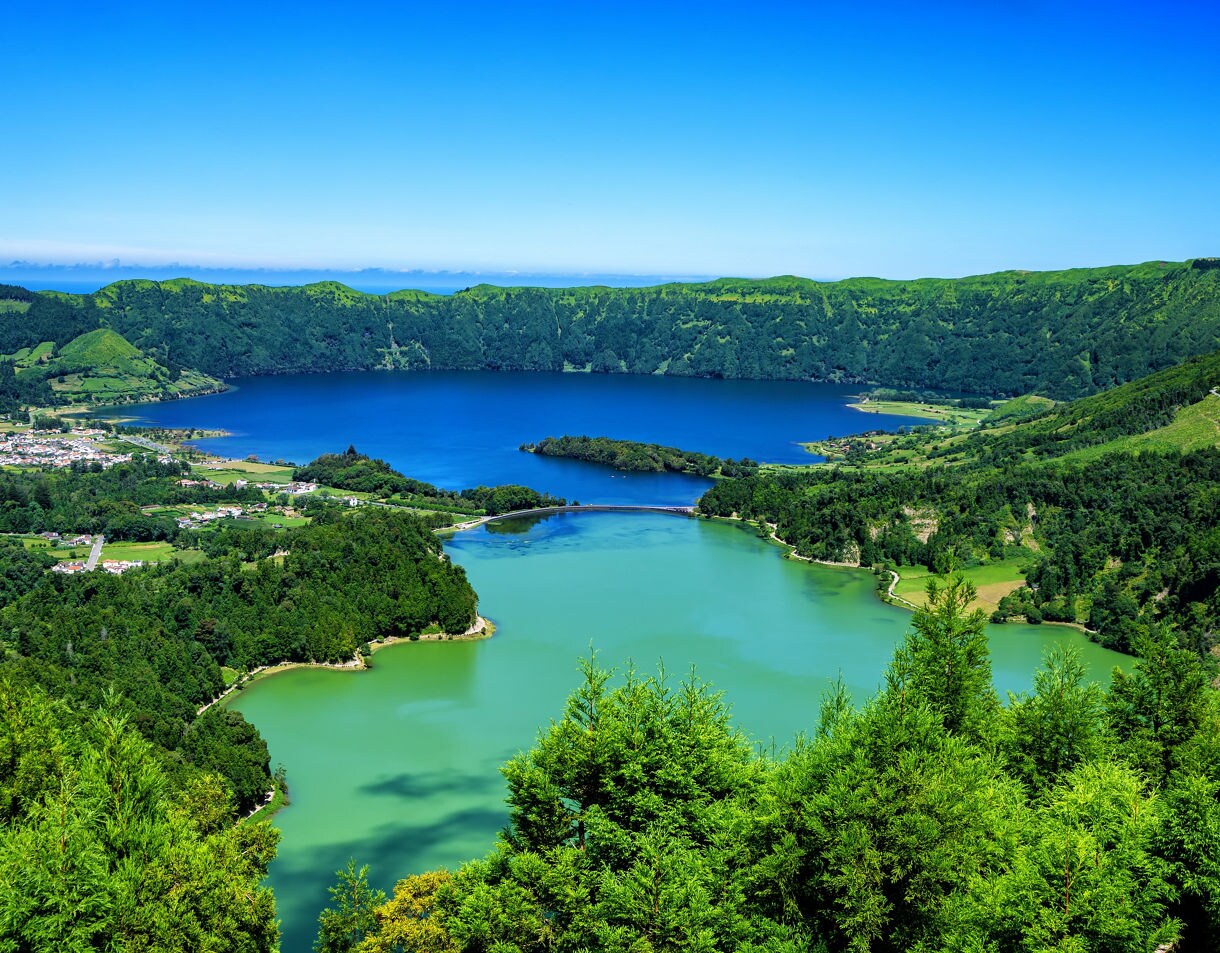 Panoramic view of Sete Cidades crater lakes on São Miguel Island with vivid blue and green waters surrounded by lush volcanic ridges.