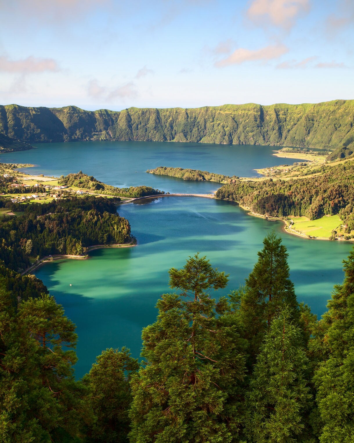 Elevated view of Sete Cidades’ twin crater lakes on São Miguel Island, with vivid blue and green waters surrounded by forested hills and steep volcanic walls.