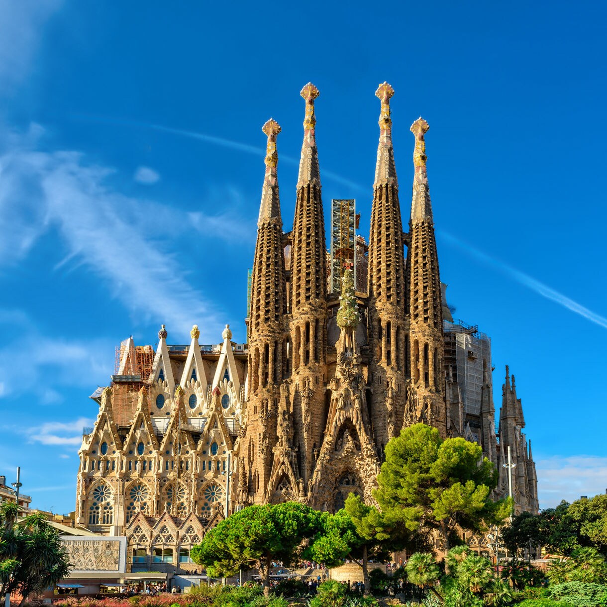 The Sagrada Família basilica at dusk, its intricate spires bathed in warm light beneath a sky of pink and orange clouds.