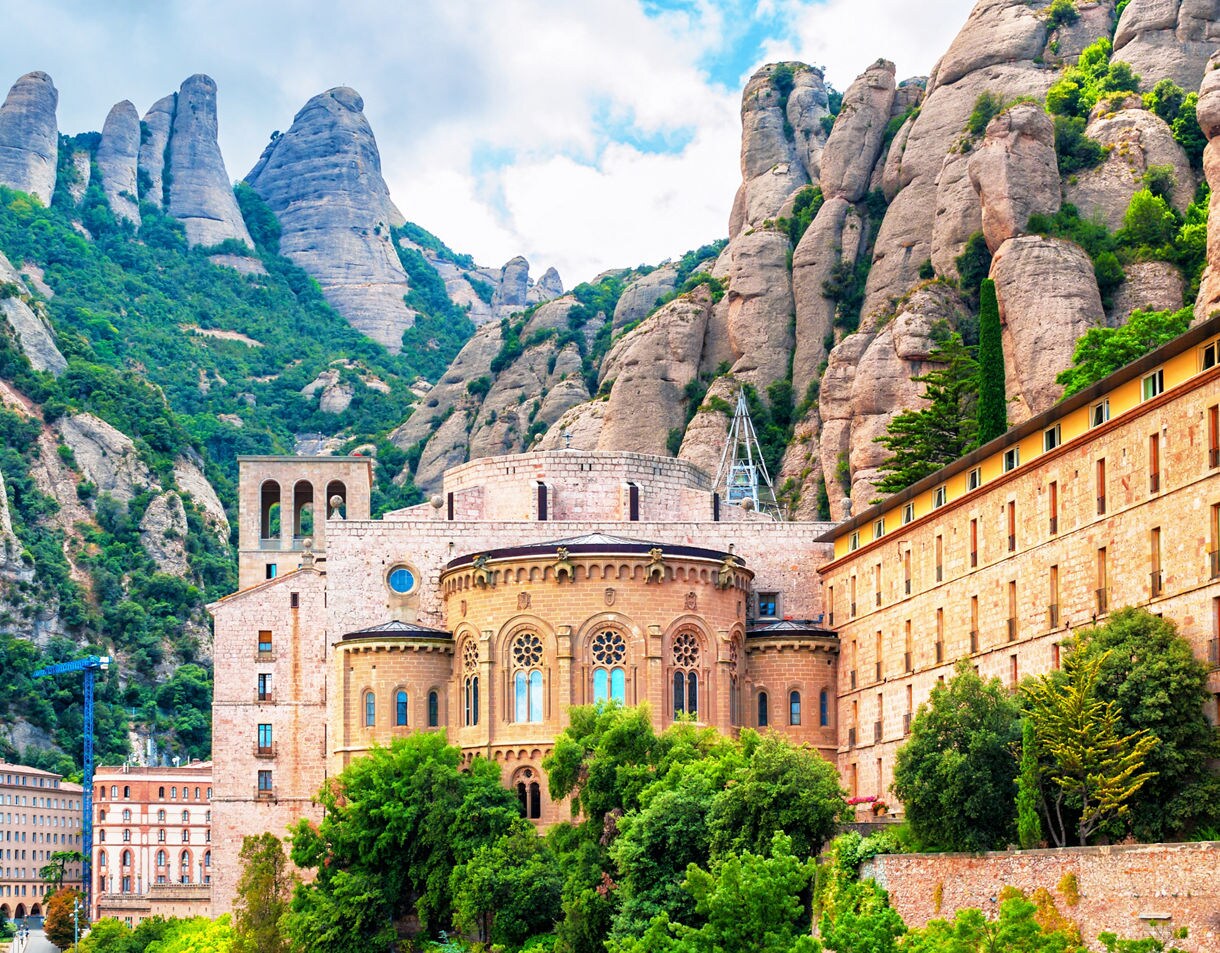 The Montserrat Monastery in Catalonia framed by rugged limestone peaks and lush greenery.