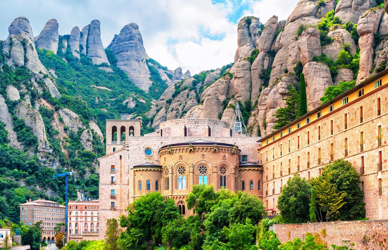 The Montserrat Monastery in Catalonia framed by rugged limestone peaks and lush greenery.