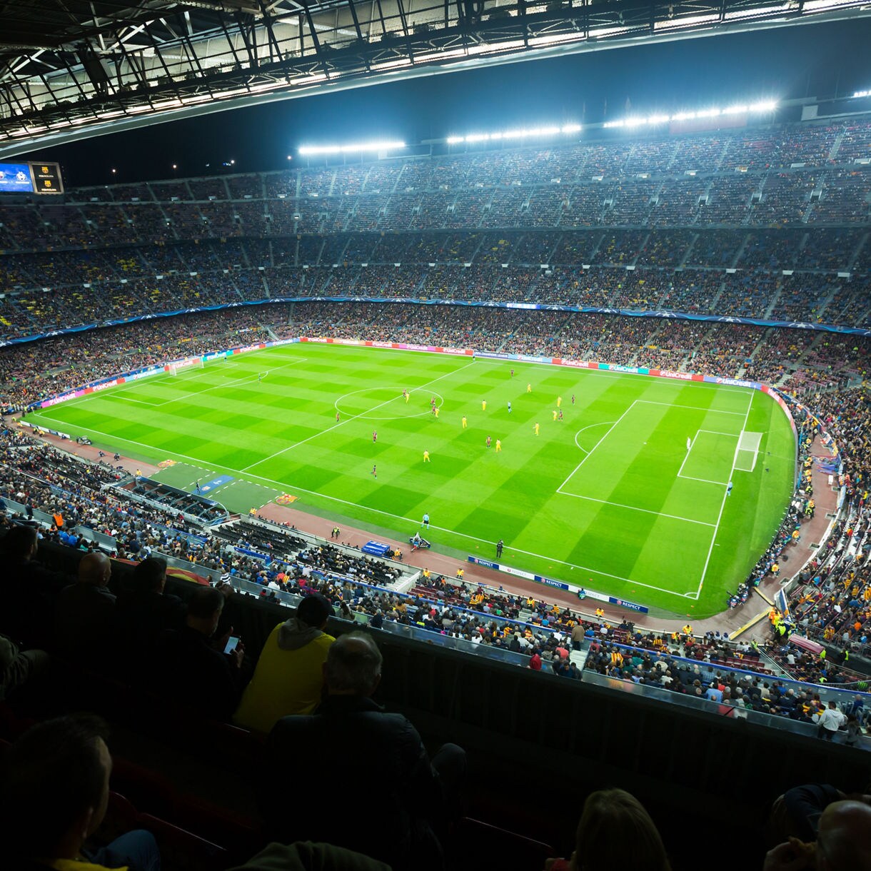 Wide-angle view of a packed Camp Nou stadium in Barcelona during a nighttime football match.