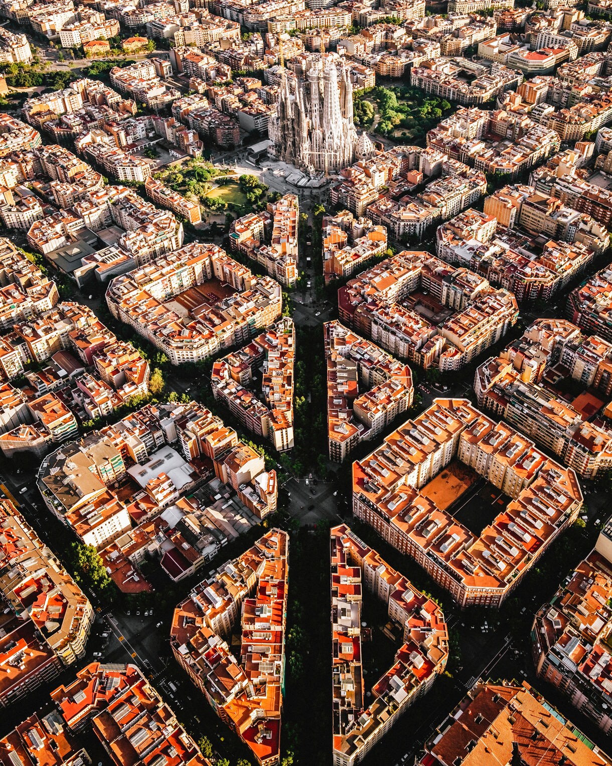 Aerial view of Barcelona’s grid-like streets with the Sagrada Família basilica standing prominently among surrounding buildings.