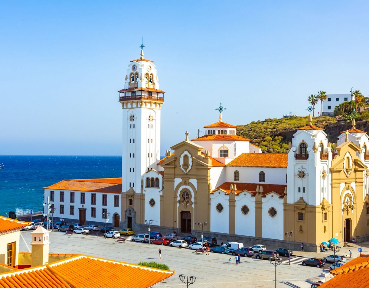 Basilica de Candelaria in Tenerife with white walls, terracotta roofs and a tall bell tower overlooking the Atlantic Ocean.