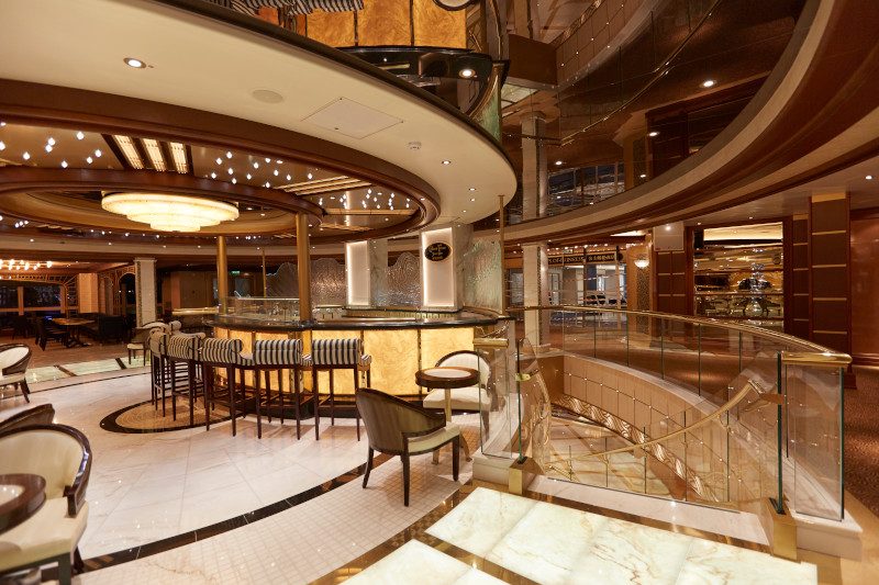 Luxurious bar area with circular ceiling fixture and high-backed chairs.