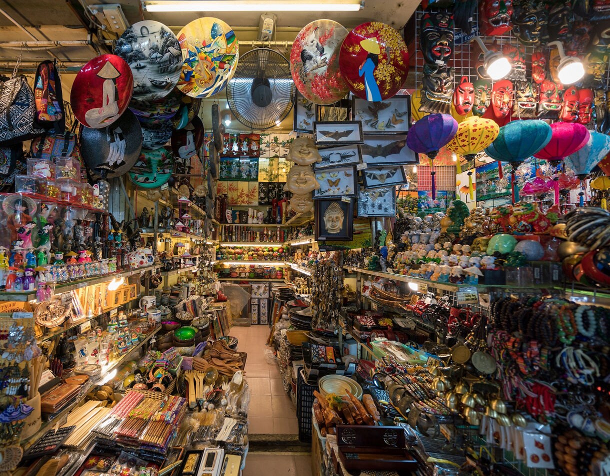 Colorful stalls at Ben Thanh Market packed with Vietnamese crafts, lacquer plates, lanterns, jewelry and figurines under warm lights.
