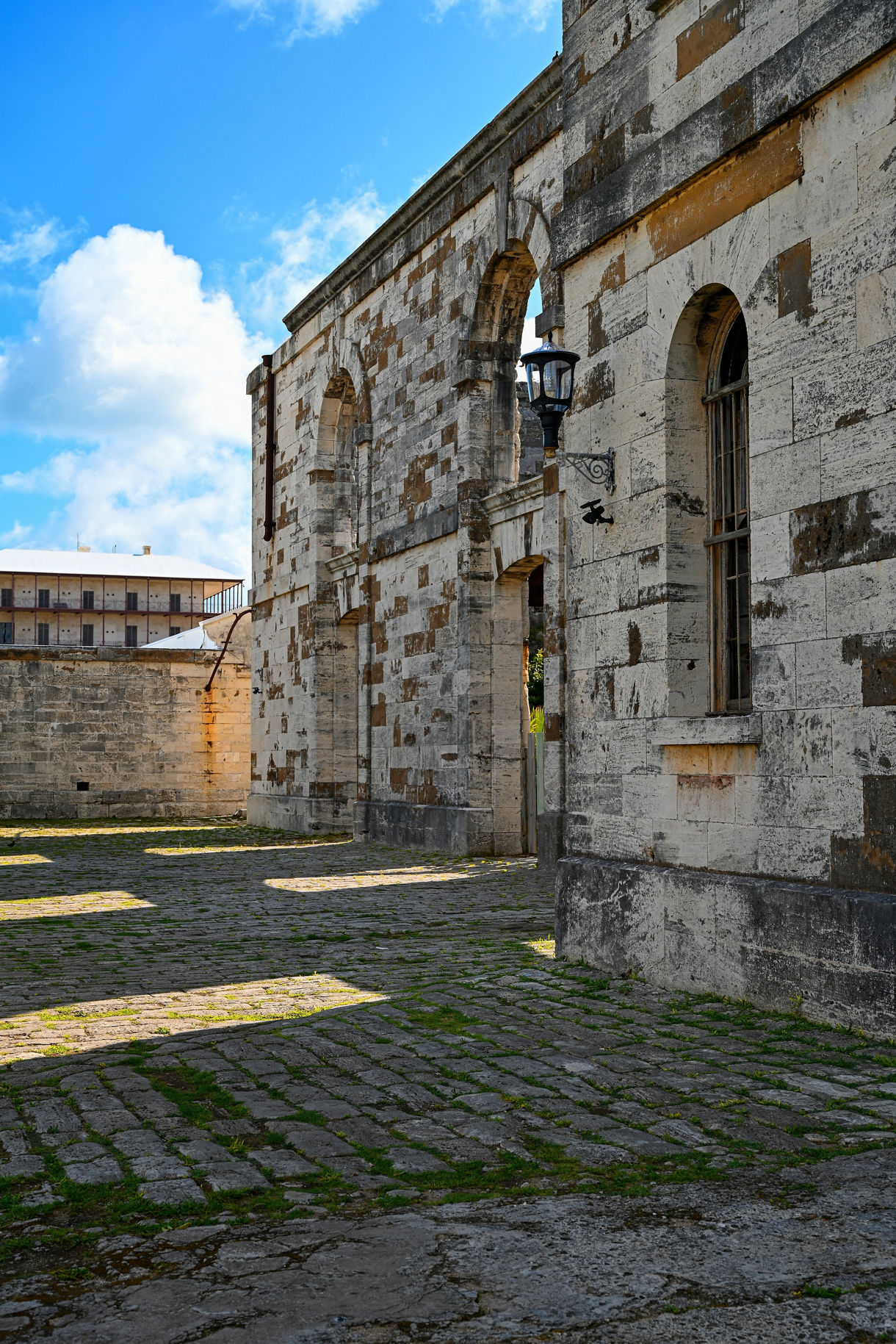 Weathered stone walls and arches in Bermuda’s Old Town with cobblestone ground and bright blue sky.