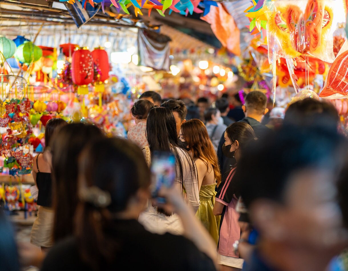 Crowds browsing stalls packed with colorful lanterns and festive decorations at Cholon Market in Ho Chi Minh City.