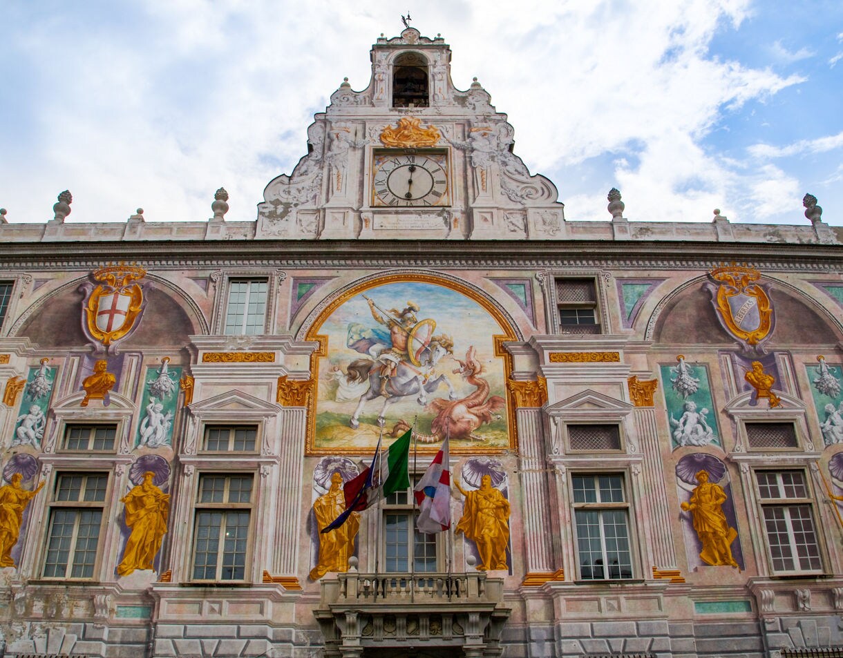 Ornate façade of Genoa’s Palazzo San Giorgio, featuring colorful Renaissance frescoes of St. George slaying the dragon and intricate sculptural details.