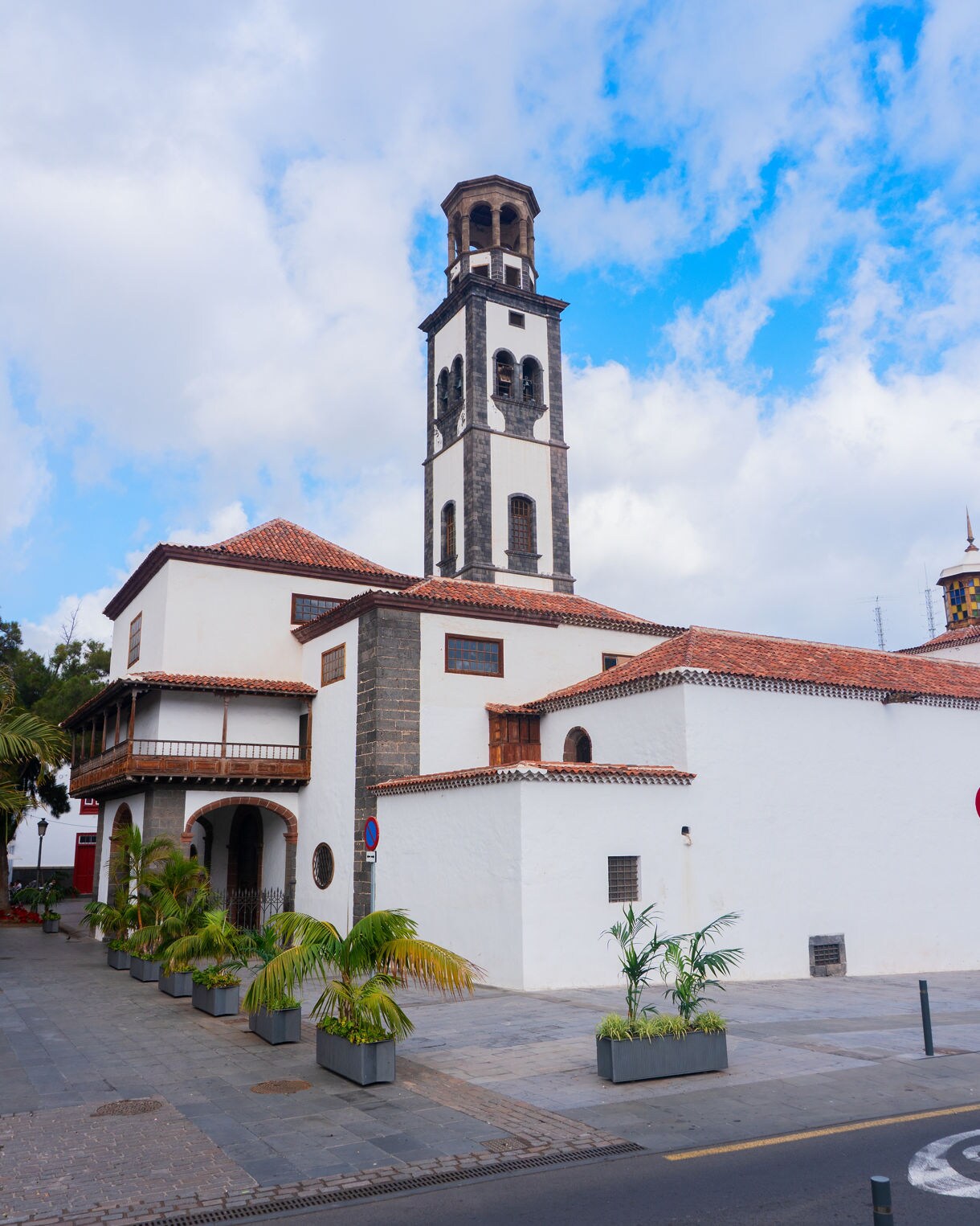 Whitewashed Church of the Immaculate Conception in Santa Cruz de Tenerife featuring a tall stone bell tower and red-tiled roof.