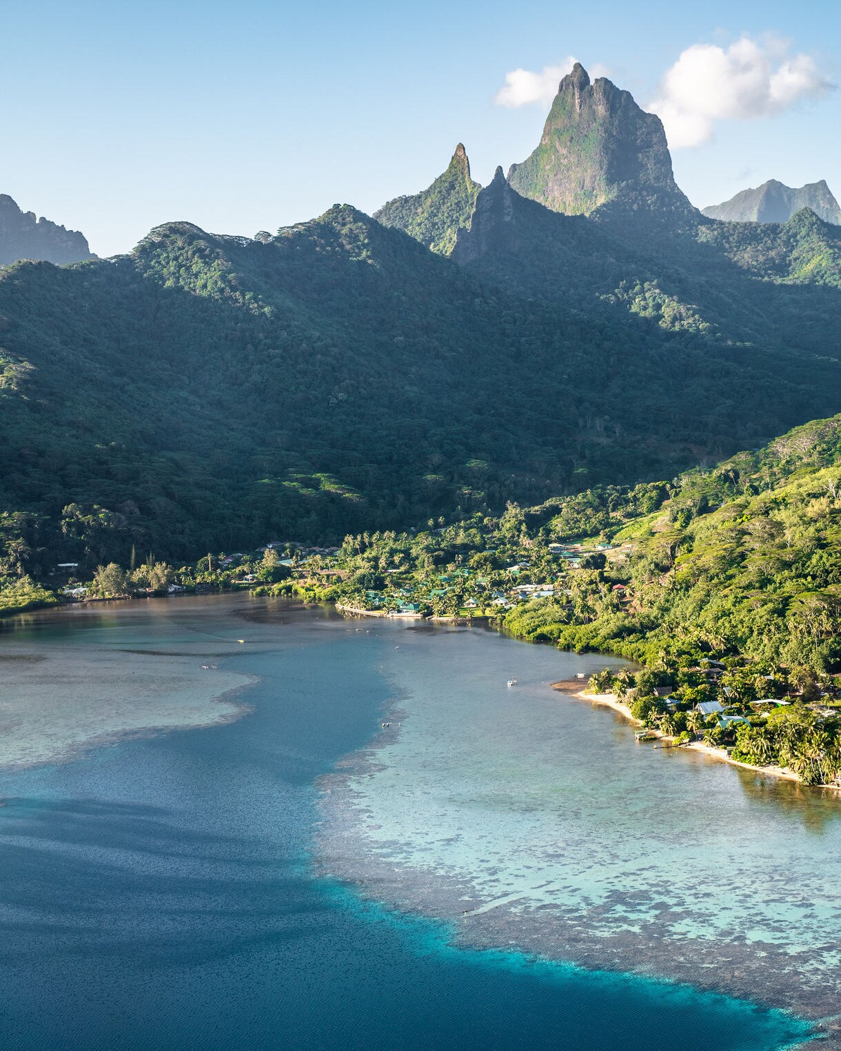 erial view of Moorea’s dramatic green mountains and coastal lagoon with vibrant blue waters.