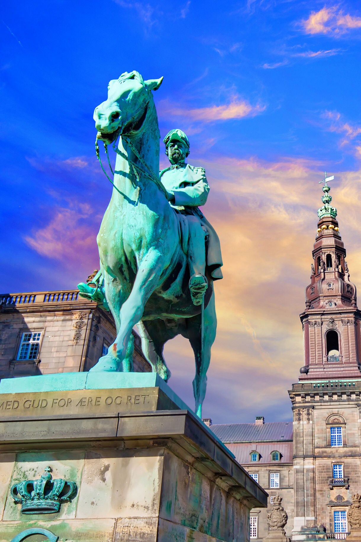 A majestic statue of a horse and rider in front of Christiansborg Palace in Copenhagen, Denmark, with the grand architecture of the palace in the background.