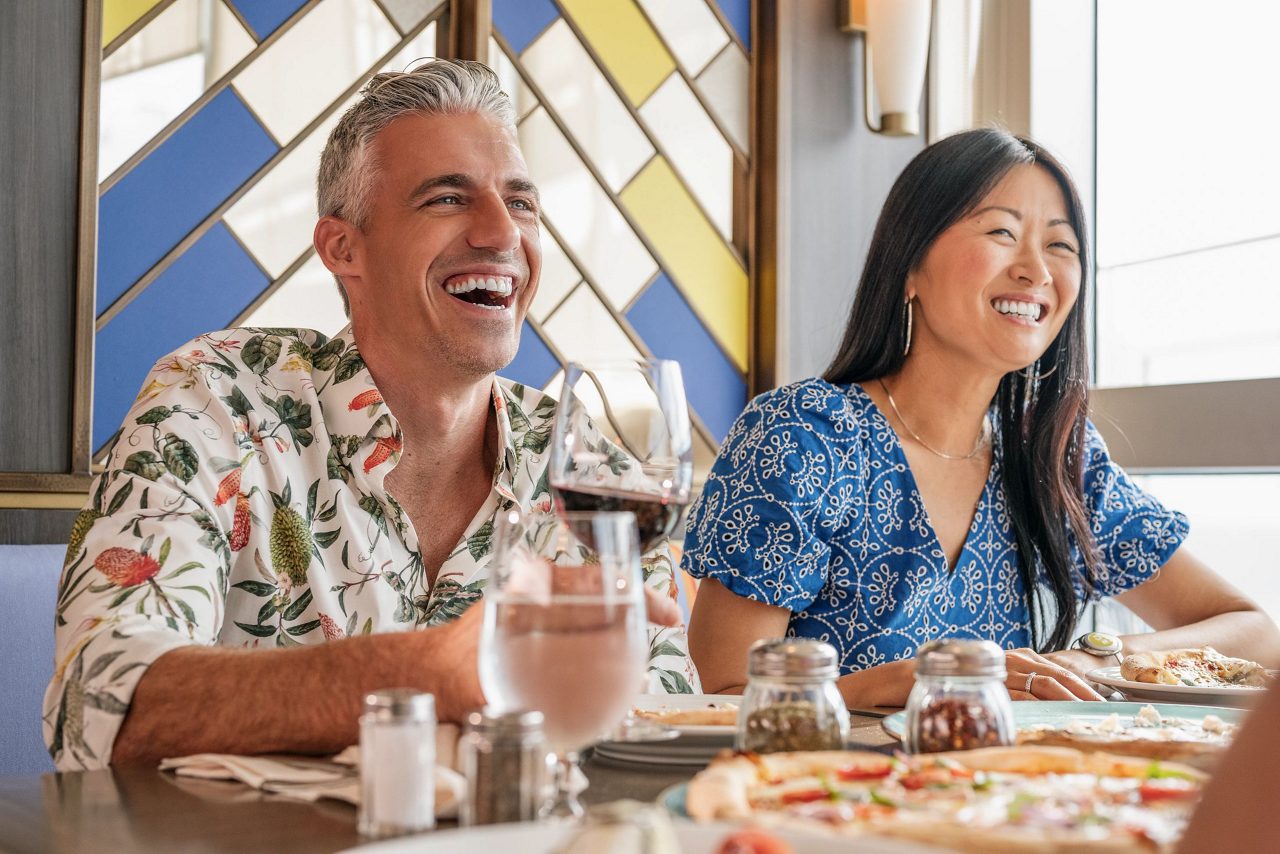 Close-up of diners enjoying margherita pizza with fresh basil and buffalo mozzarella. 