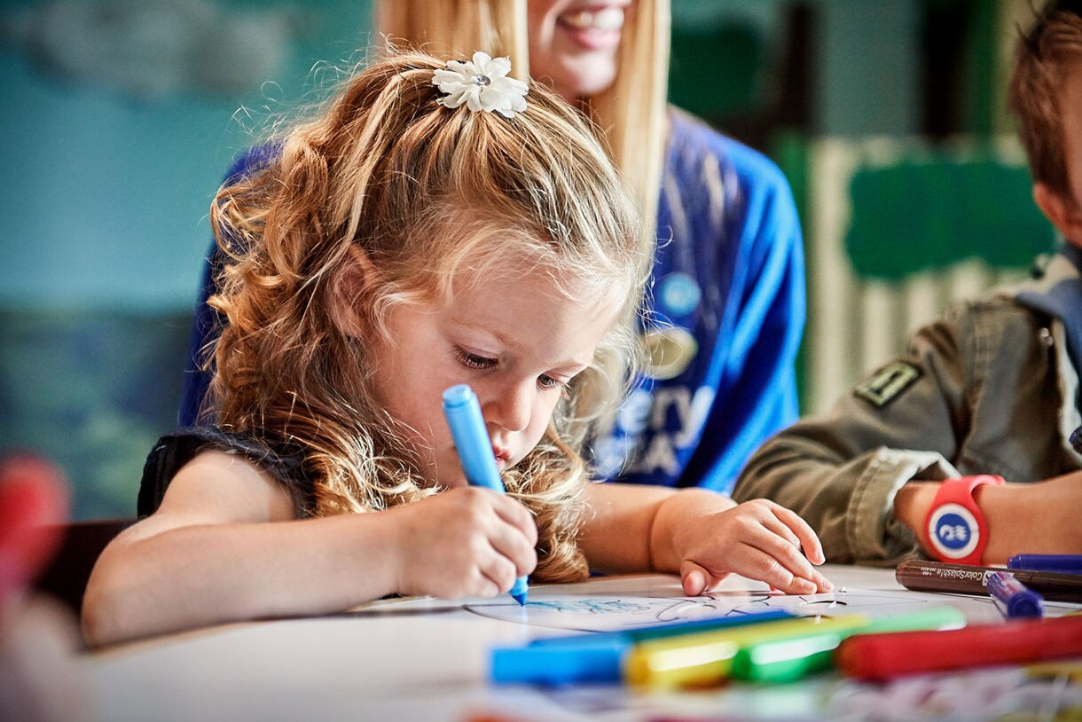 A little girl sits at a table coloring