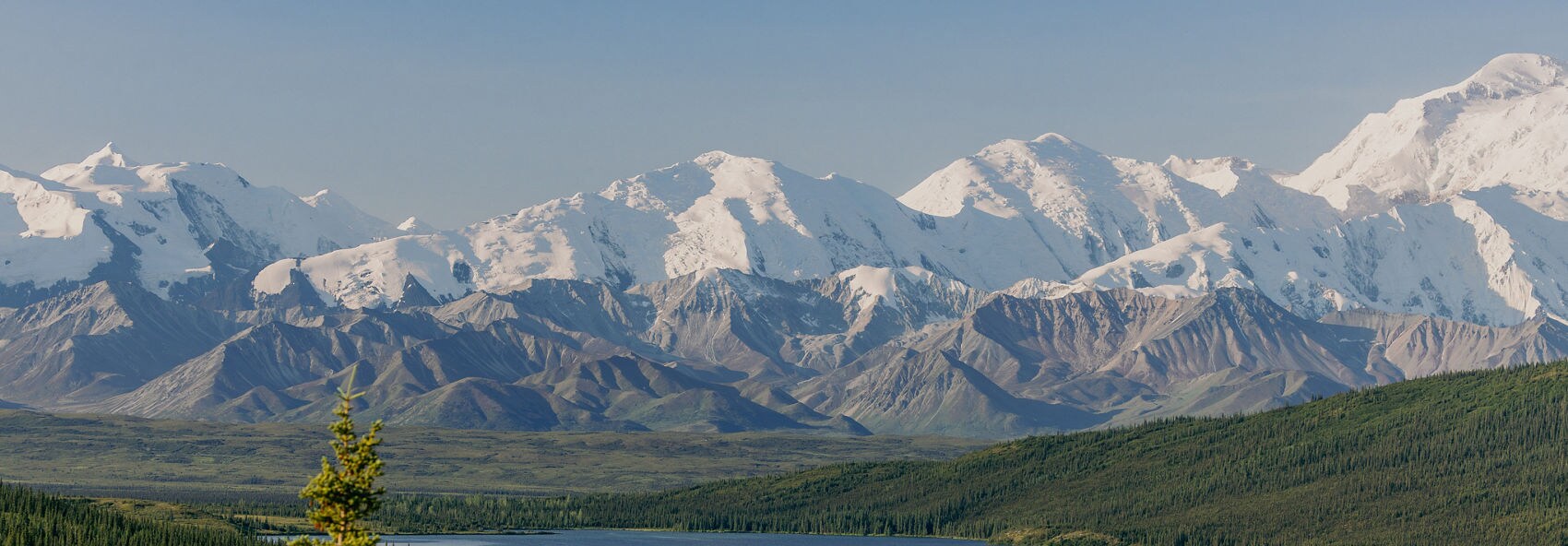 A joyful couple walking along a beach at the edge of clear turquoise water. They appear to be laughing and enjoying their time together in a tropical setting. The beach scene is calm, with the horizon visible under a cloudy sky.