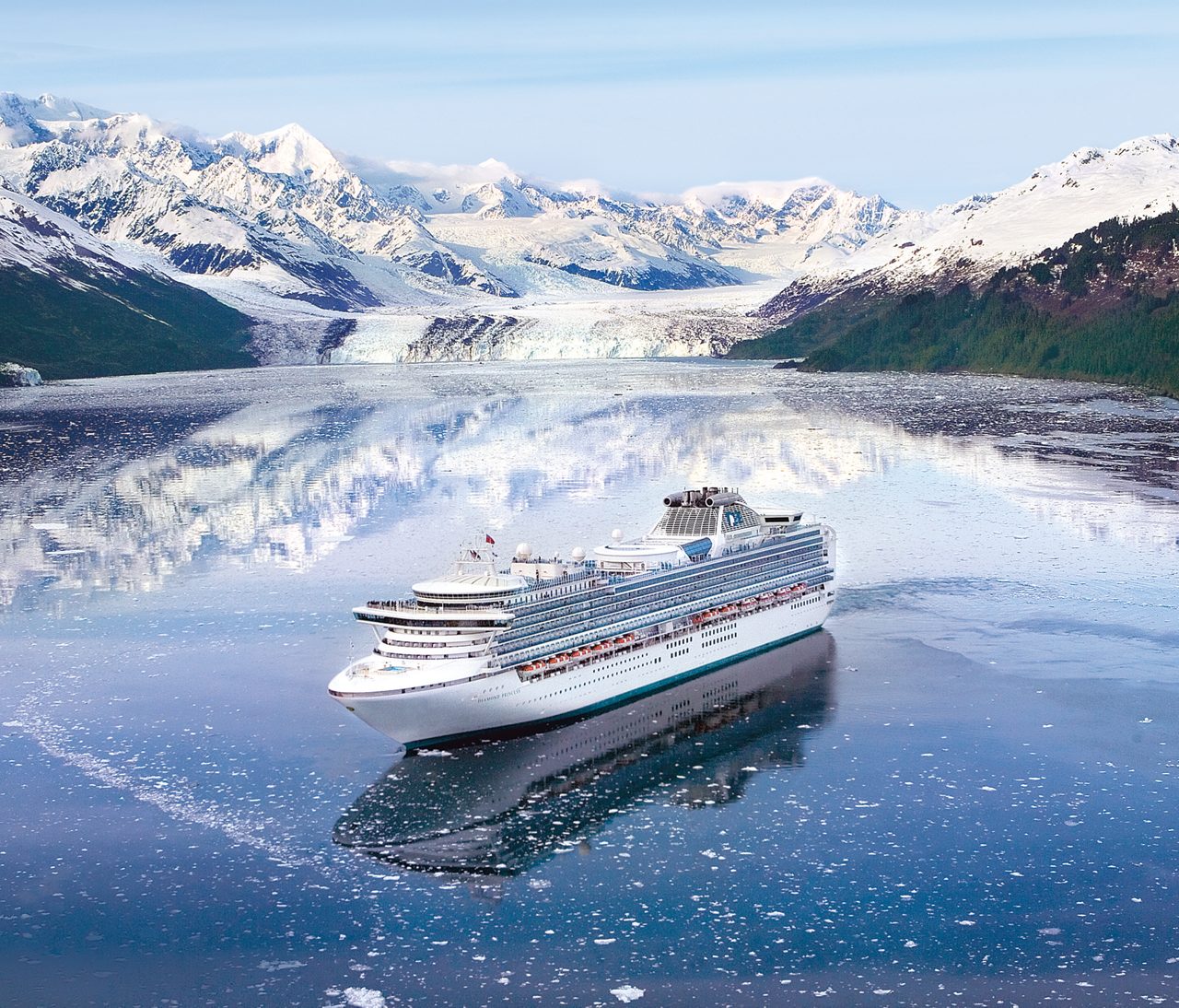 Diamond Princess ship sails through pristine icy waters surrounded by snow-capped mountains and glaciers. The serene setting highlights the natural beauty of Alaska, with floating ice fragments visible in the foreground. The ship's design and scale emphasize luxury travel in a remote and breathtaking environment.