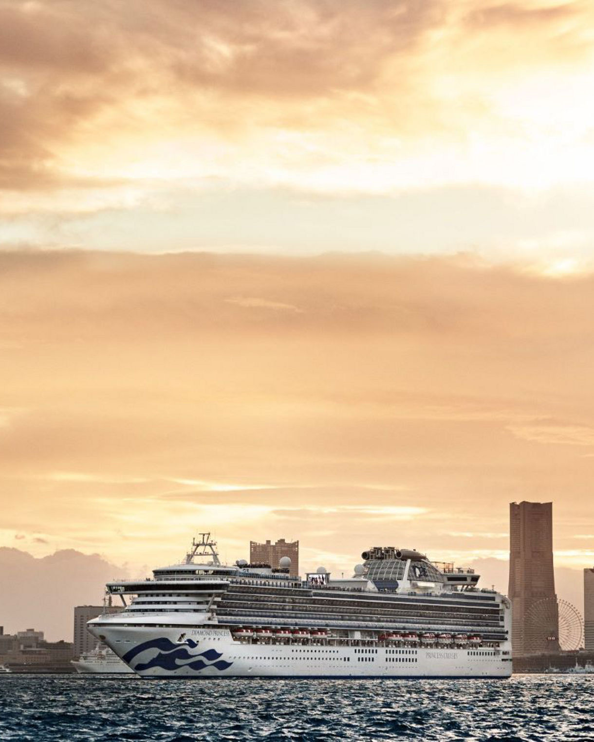 A view of the Diamond Princess cruise ship cruising on calm waters with a city skyline and a warm, golden sunset in the background.