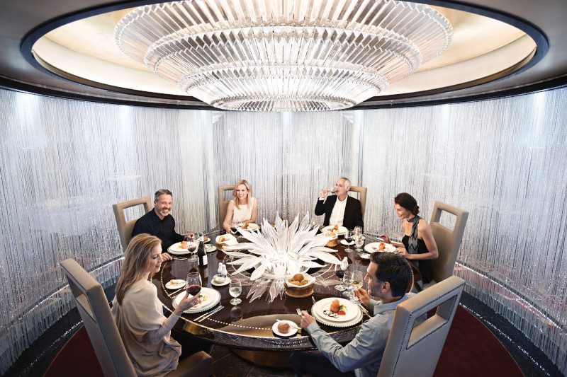 An elegant private dining room with a glass dome ceiling, featuring a round table where guests are seated for an exclusive chef's table experience.