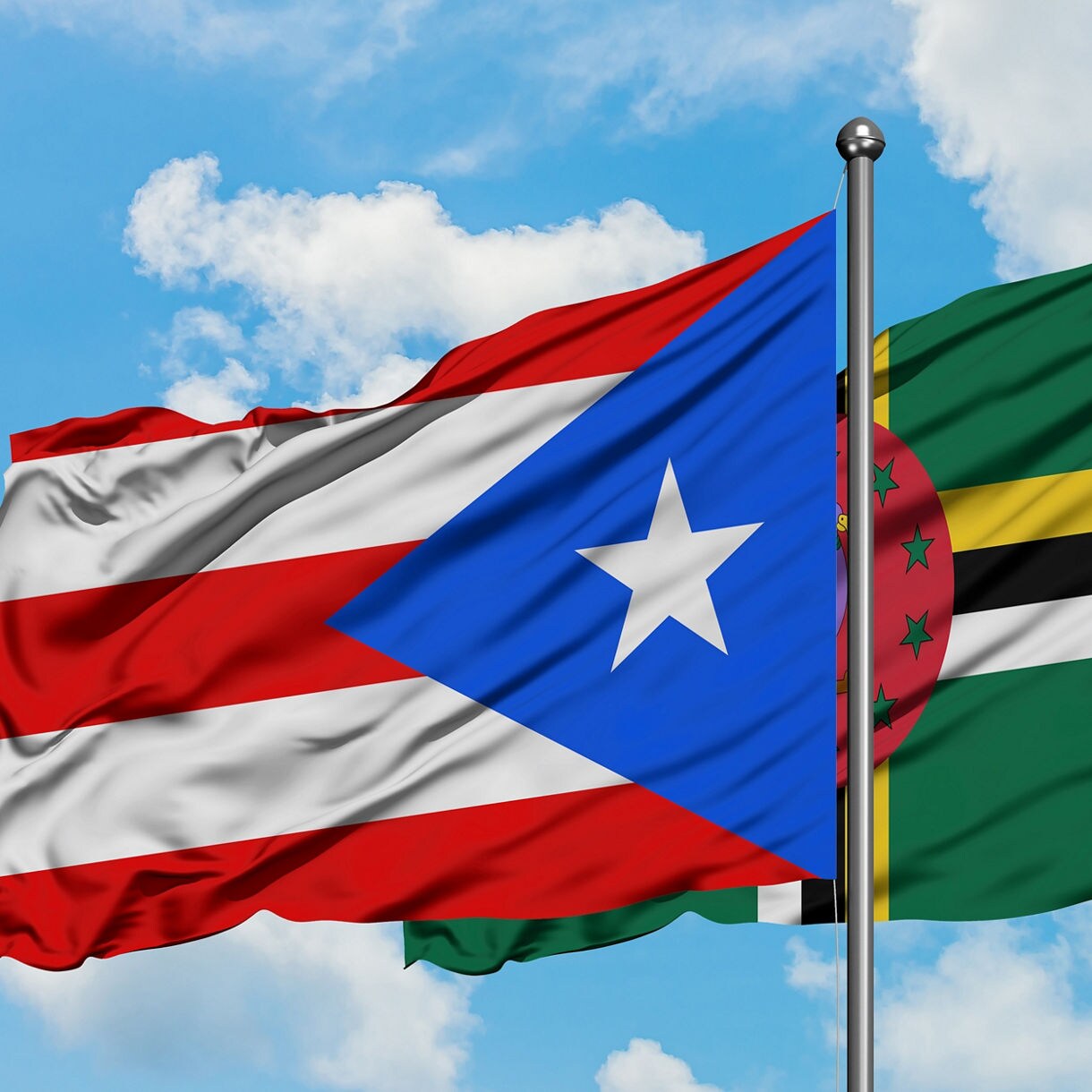 Dominica and Puerto Rico flag waving in the wind against white cloudy blue sky together. Diplomacy concept, international relations.