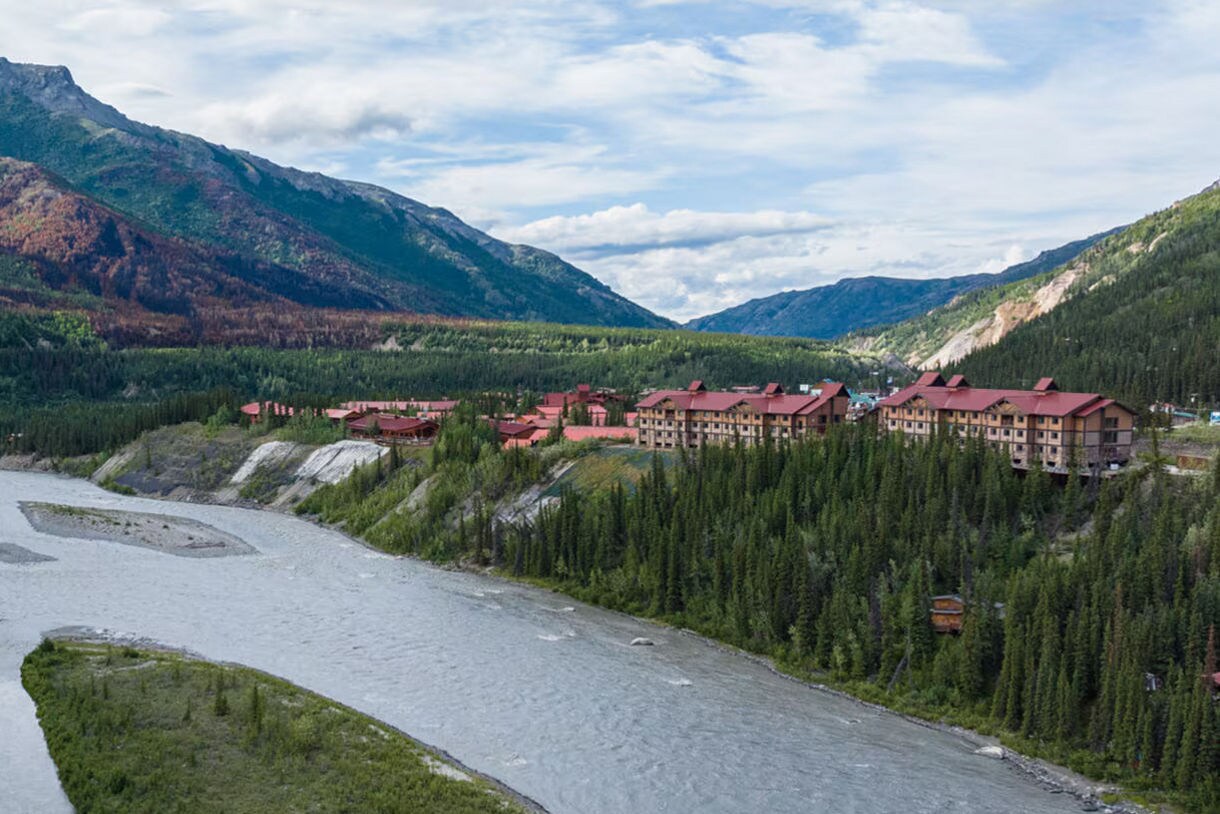 A stunning view of the Nenana River winding through the rugged terrain near the Denali Princess Wilderness Lodge®, framed by lush greenery and dramatic mountain scenery.