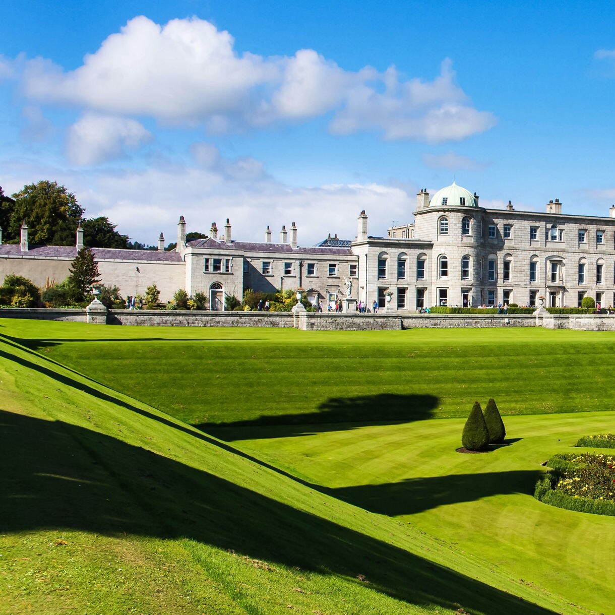 Tourists visiting Powerscourt Gardens, view on mansion from hill